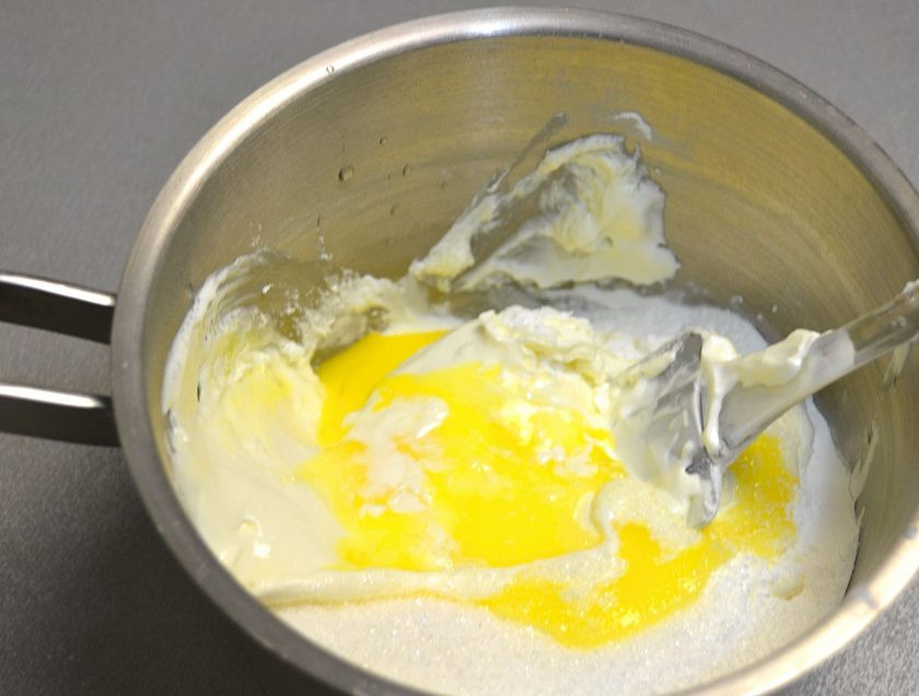 1. Этап. Мандариновый торт на Новый год: Пока выпекается торт, займитесь кремом. Для этого смешайте сметану, 1 желток, 150 грамм сахара, 5 грамм ванильного сахара и 20 грамм крахмала.