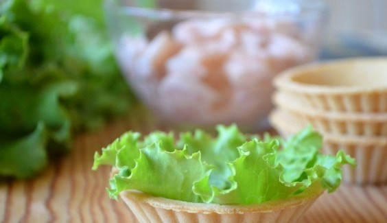 1. Этап. Тарталетки с морепродуктами: Вымойте листья салата, обрежьте их по форме и размеру тарталеток. Выложите салат в корзинки.
