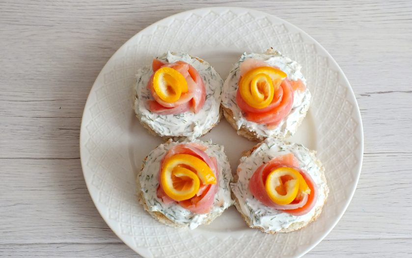 1. Этап. Бутерброды по-сахалински: Ломтики лимона скрутите в цветочек. Установите в серединку красной рыбы.