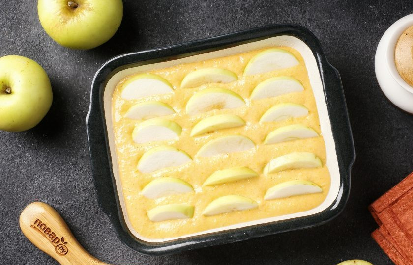 1. Этап. Тыквенный пирог с яблоками: Форму для запекания смажьте маслом. Дно и бока присыпьте мукой или манкой. Выложите тесто. Яблоки вымойте, удалите сердцевинки и нарежьте дольками. Вставьте яблоки, вдавливая чуть в тесто.