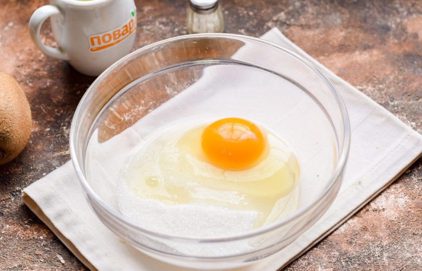 1. Этап. Пирог с киви на сметане: Переложите в миску куриное яйцо, добавьте сахарный песок.