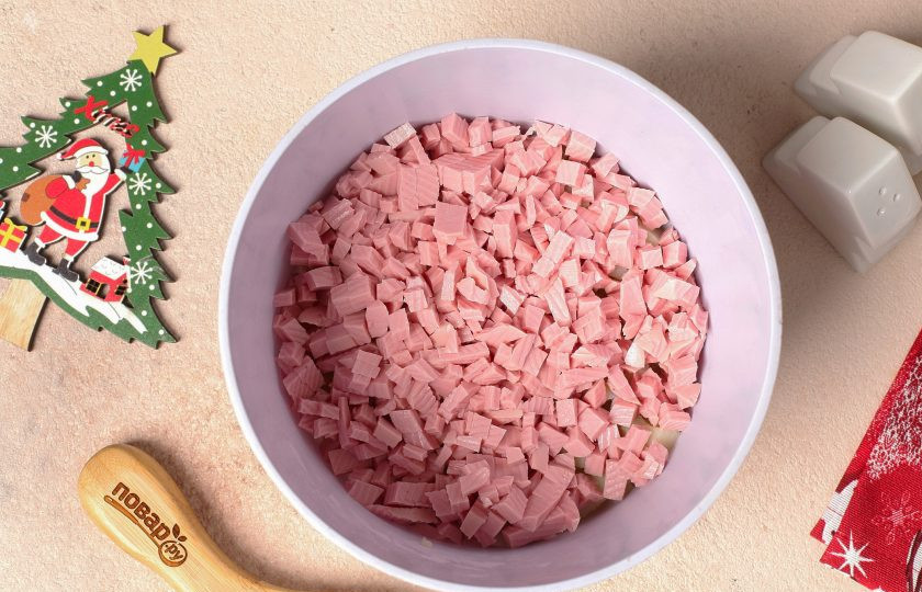 1. Этап. Салат Оливье на год Кролика: Добавьте нарезанную небольшими кубиками варёную колбасу. Варёную колбасу можно заменить на копчёную, буженину, грудинку или любое отварное мясо.