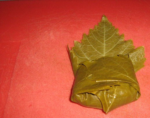 1. Этап. Долма азербайджанская: 6. С виноградного листа срежьте жесткую часть, которая крепится к черешку. На середину листа выложите фарш и заверните, чтоб получился конвертик, закрытый со всех сторон.