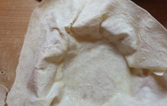 1. Этап. Лаваш с вишней: Возьмите среднюю форму для запекания. Выложите один лаваш, смажьте хорошенько сметанным соусом, потом сверху накройте вторым лавашем. Посыпьте сахаром, но не всем.