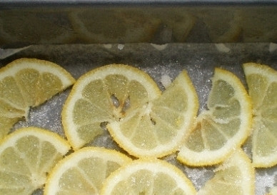 1. Этап. Шарлотка с лимоном: Форму для выпечки обязательно застилаем пергаментной бумагой. Выкладываем ломтики лимона и посыпаем их сахаром.
