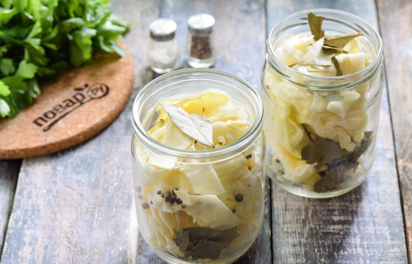 1. Этап. Капуста пластами на зиму: Подготовьте стерильные банки. Наполните их капустой, между слоями выложите лавровый лист и перец горошком.