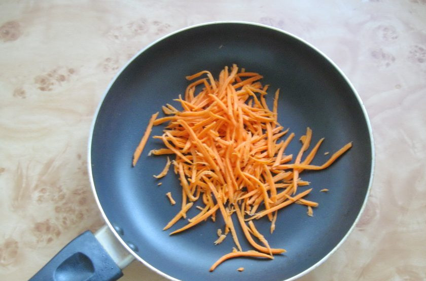 1. Этап. Салат с курицей и лапшой из омлета: Пока филе варится, морковь очистите, помойте и нарежьте соломкой. Выложите в сковороду.