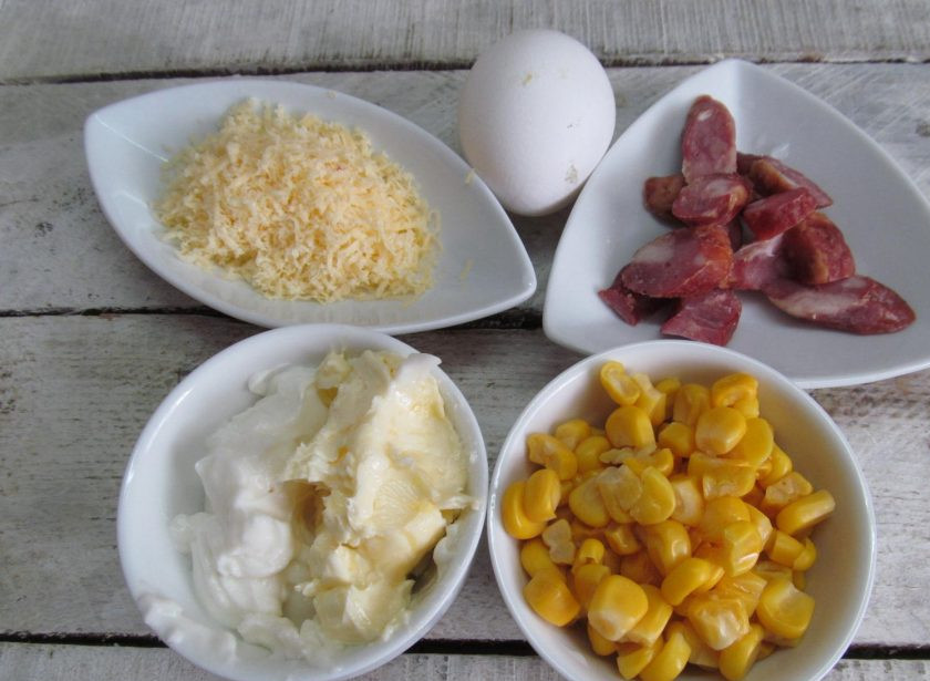 1. Этап. Закусочный кекс с кукурузой, колбасой и пармезаном: Подготовить необходимые продукты. Сыр натереть на мелкой терке. Колбасу нарезать маленькими кусочками, слить жидкость с консервированной кукурузы.