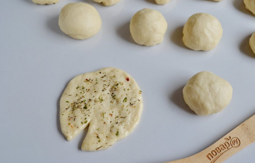 1. Этап. Круассаны-рогалики с прованскими травами: Смажьте рабочую поверхность растительным маслом. Каждый шарик раскатайте так, чтобы с одной стороны был вытянутый край, а другой край разрежьте, как на фото. Смажьте лепешку растительным маслом с двух сторон, посыпьте прованскими травами с внутренней стороны.