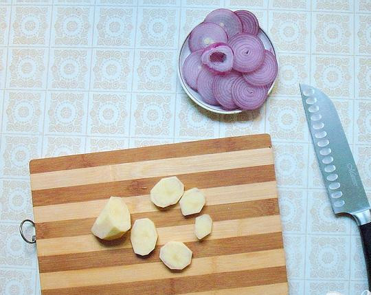 1. Этап. Конгрио с картофелем: 2. От кожуры очищаем картофель и лук, колечками их нарезаем. Соком лимона немного поливаем кусочки картофеля, для того чтобы кусочки картофеля не потемнели. На тридцать минут замаринуем кольца лука в соке лимона смешанном с водой в пропорции 1:1. Чтобы картофель не стал водянистым, в воде его замачивать не надо.