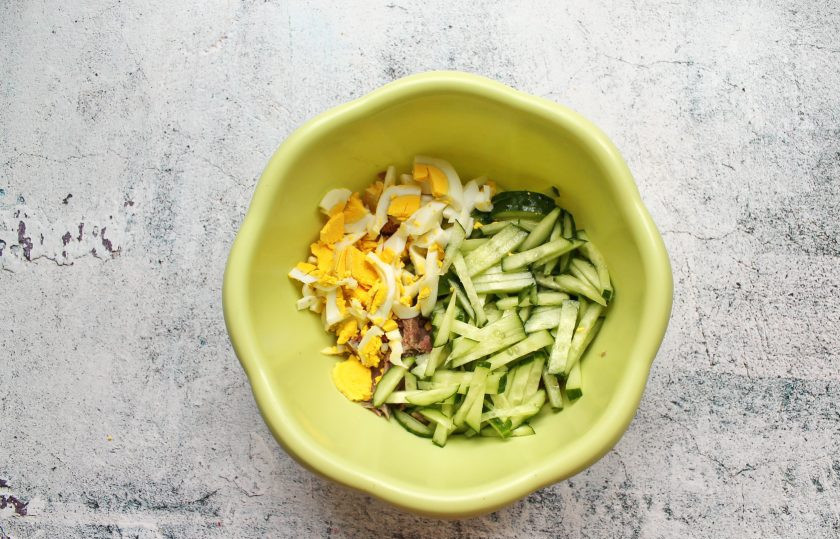 1. Этап. Салат Праздничный с говяжьим языком: Огурец и отварное яйцо порежьте соломкой и выложите к языку.