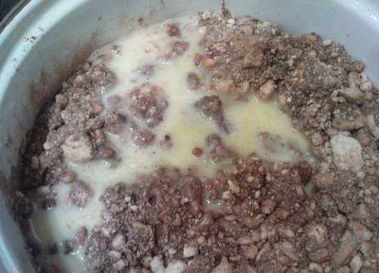 1. Этап. Пирожное Колбаска из печенья: Сливочное масло растопите на плите и дайте ему немного остыть. К печенью добавьте сгущённое молоко и какао. Затем туда же добавьте сливочное масло и аккуратно перемешайте массу так, чтобы она стала однородной.