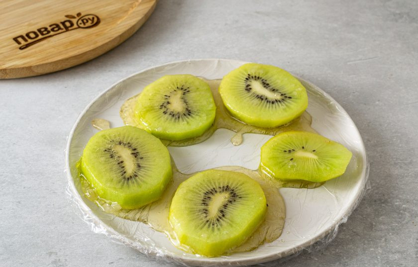 1. Этап. Киви в карамели: Снимите с плиты кастрюлю. Обмакните киви в карамель. Выложите на пищевую пленку смазанную растительным маслом. Дайте застыть.