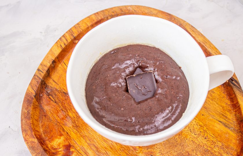 1. Этап. Шоколадный фондан в микроволновке: Перелейте тесто в чашку емкостью не менее 400 мл. В середину теста утопите кусочки шоколада.