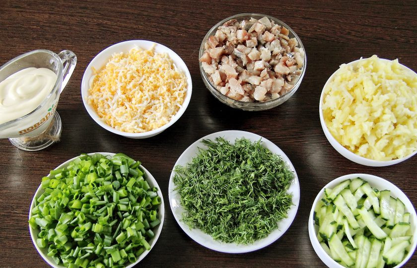 1. Этап. Салат Зеленая шуба: Нарежьте кубиками филе сельди. Огурец нарежьте кубиками или небольшой соломкой. Картофель очистите и натрите на крупной терке, яйца натрите на мелкой. Лук и укроп измельчите ножом.