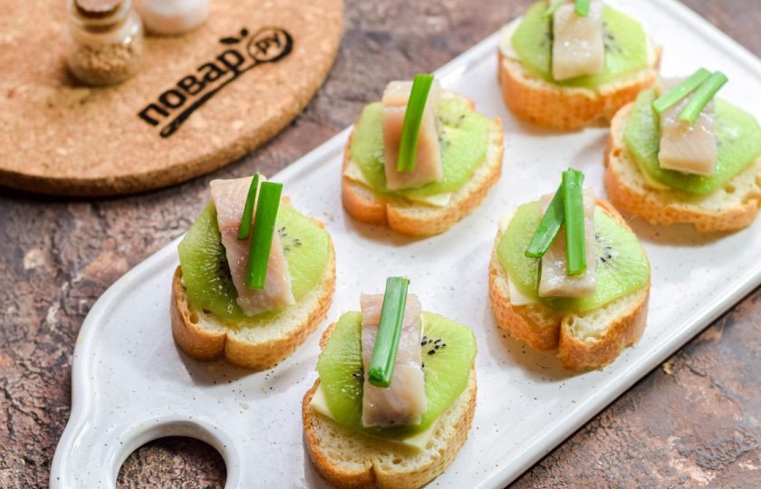 1. Этап. Бутерброды с селедкой и киви: Добавьте на каждый бутерброд по несколько перьев зеленого лука.