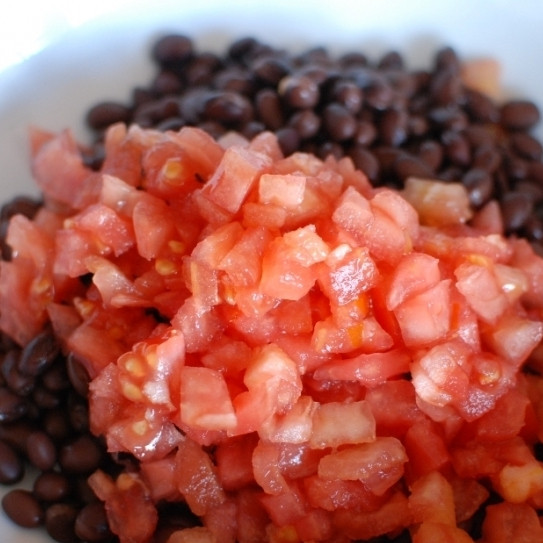 1. Этап. Салат с черной фасолью: Смешиваем в салатнице помидоры и фасоль.