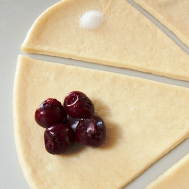 1. Этап. Вишневые бухты: В центр каждого треугольника кладем немножко сахара и несколько ягод вишни (без косточек).