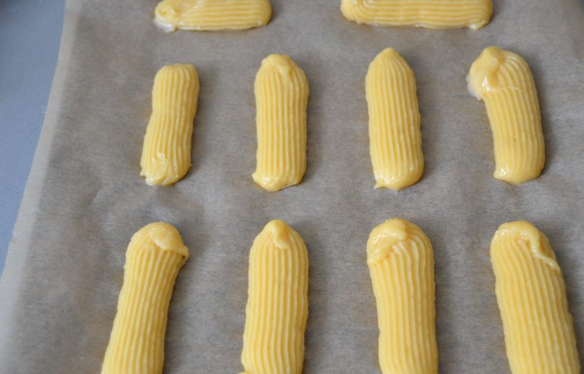 1. Этап. Фисташковые эклеры: Переложите тесто в кондитерский мешок и отсадите на противень застеленный бумагой для выпечки.