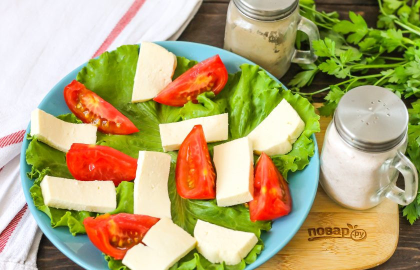 1. Этап. Белковый салат на ужин: Фету нарежьте ломтиками и выложите между томатной нарезки на листовой салат.