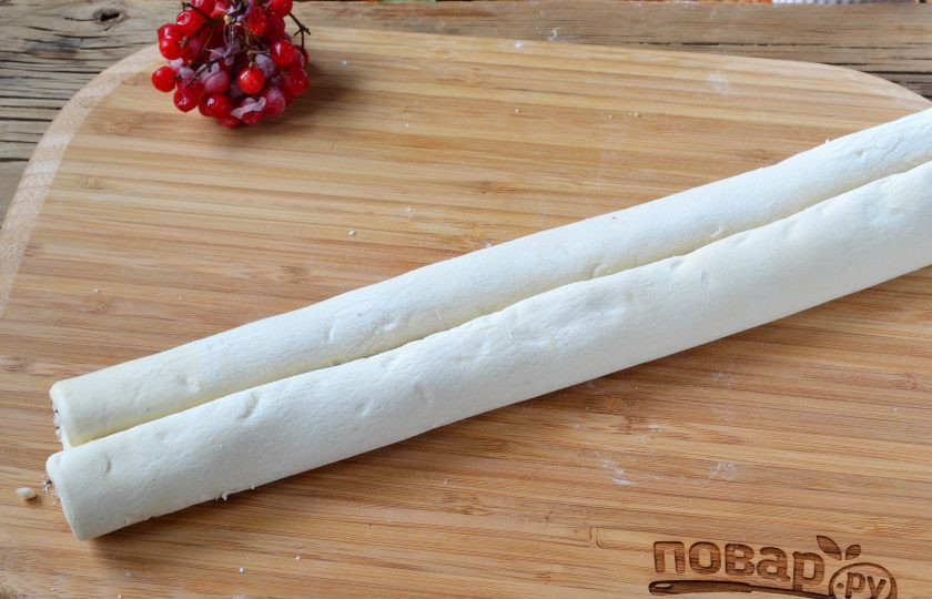 1. Этап. Ушки-завитушки: С двух концов заверните тесто в рулетик, который сходится посредине, чтобы получился длинный двойной рулетик.