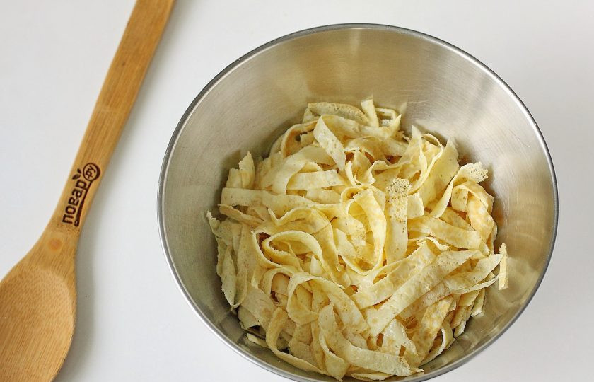 1. Этап. Блинный салат: Разрежьте блины пополам, сложите стопочкой и нарежьте полосками. Переложите блинчики в глубокую миску.