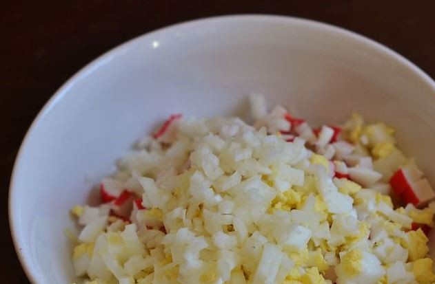 1. Этап. Салат с крабовыми палочками, яйцом и майонезом: Репчатый лук очистите и нашинкуйте. Выложите его в миску. Чтобы лук не горчил, вы можете предварительно вымочить его в воде с добавлением уксуса или лимонного сока.