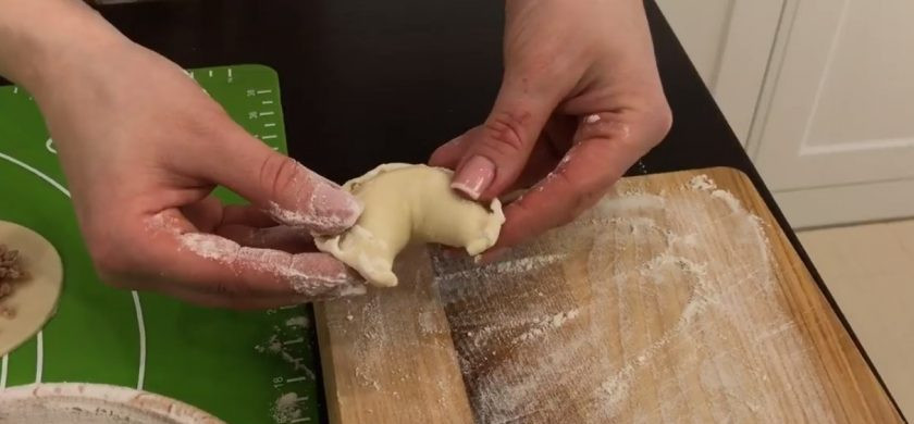 1. Этап. Вареники с мясом на заварном тесте: 6. Выложите начинку на заготовленные круги теста, сформируйте вареники, защипнув края теста полумесяцем. Слегка согните вареники и выложите на присыпанную мукой доску.