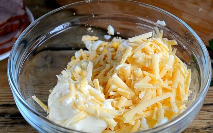 1. Этап. Рулетики из ветчины: Смешайте яйца и сыр, выдавите несколько зубчиков чеснока.