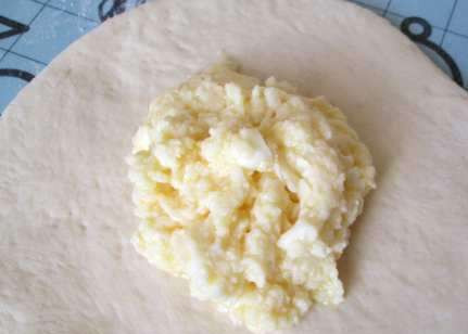 1. Этап. Хачапури с сыром в мультиварке: Ближе к окончанию расстойки теста, трем сыр на крупной терке, добавляем к нему яйца и сливочное масло, перемешиваем все. Готовое тесто делим на 9-10 равных частей и раскатываем каждую в плоскую лепешку. Выкладываем в середину лепешки немного начинки и соединяем сверху плотно края теста, скалкой раскатываем немного хачапури, чтобы придать ему плоскую форму, то же самое повторяем с остальными кусочками теста.