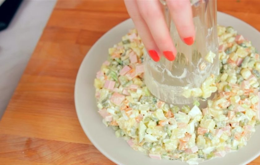 1. Этап. Новогодний венок из оливье: 3. Далее сформируйте венок из салата. Для этого в центр тарелки поставьте стакан и выложите вокруг стакана кольцом салат.