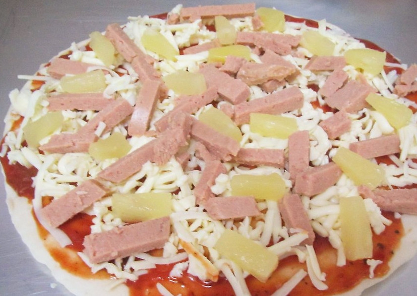 1. Этап. Пицца по-гавайски: Натрите сыр, а ветчину и ананасы порежьте небольшими кусочками. Выложите эти продукты на пиццу.
