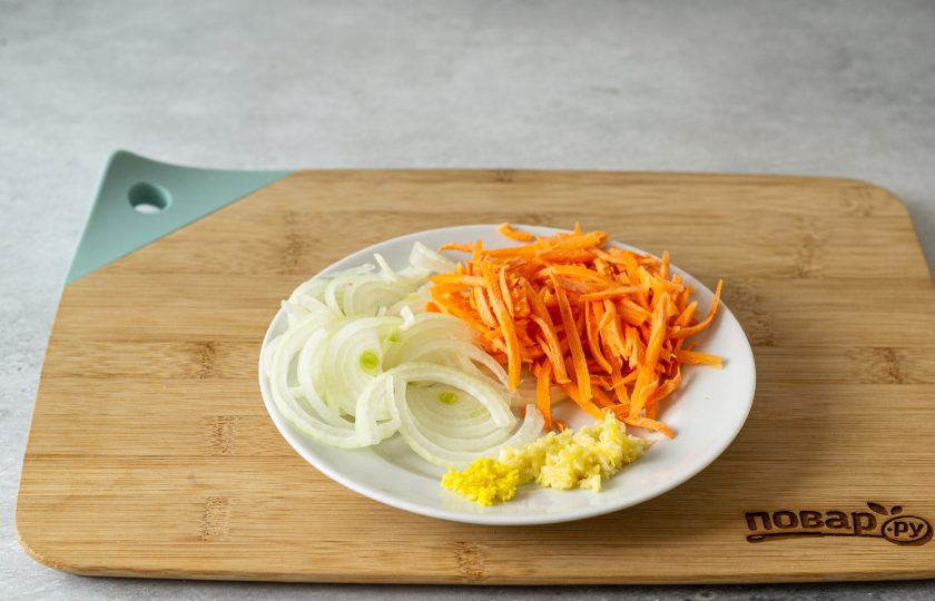 1. Этап. Капуста по-корейски на зиму: Лук нарежьте на тонкие полукольца, морковь натрите на терке для корейской моркови, а чеснок и имбирь на мелкой терке.