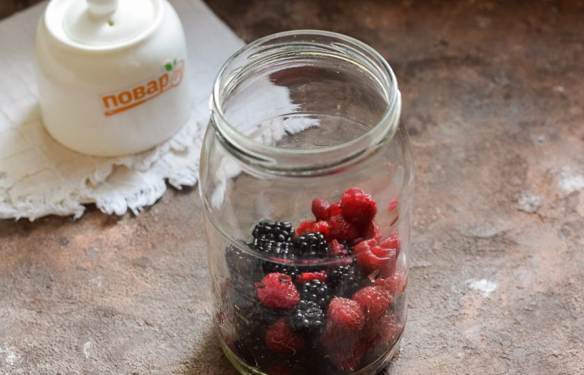 1. Этап. Компот из ежевики и малины на зиму: Банку для заготовки тщательно вымойте с пищевой содой, после ополосните хорошо под теплой проточной водой. Стерилизуйте банку удобным способом – над паром, в духовке или микроволновке. Крышку опустите в воду и проварите 10 минут. Переложите в банку малину и ежевику.