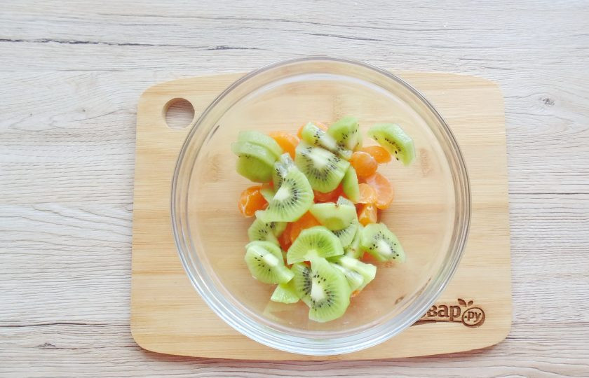 1. Этап. Фруктовый салат из мандаринов и яблок: Киви вымойте, очистите и нарежьте по размеру долек мандаринов. Добавьте в салатник.