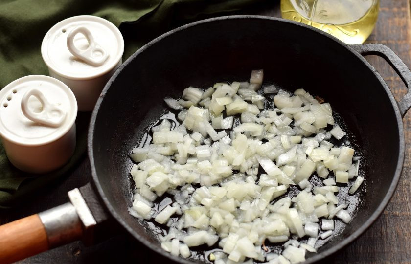 1. Этап. Гречка с кальмарами: Лук очистите, нарежьте кубиками, выложите на разогретую масляную сковороду.