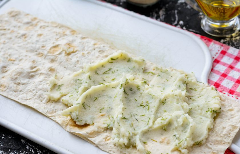 1. Этап. Пирожки из лаваша с картошкой: Нарежьте лаваш полосками примерно 9х25 см. На один край выложите 1-1,5 ст.л. начинки.