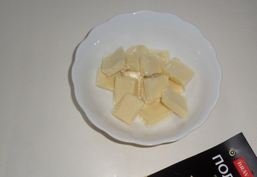 1. Этап. Кукурузно-тыквенный кекс с изюмом: В небольшую миску выкладываю белый шоколад, поломав его на кусочки. Добавляю в миску молоко. Ставлю ее в микроволновую печь.