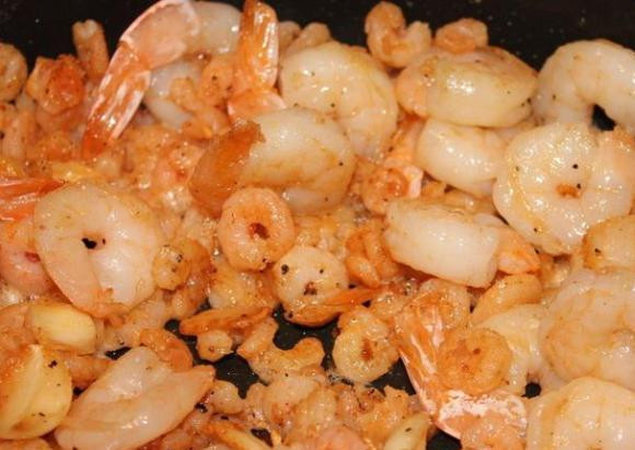 1. Этап. Волованы с креветками: Креветки отварим и почистим. Очистим чеснок и измельчим с помощью чеснокодавилки. Креветки измельчаем, несколько больших креветок оставляем целыми. Посыпаем креветки солью, перцем, поливаем соком лимона, добавляем сметану и немного тушим на сковороде.