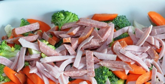 1. Этап. Запеканка с колбасой: В форме для запекания складываем овощи: морковь чистим и нарезаем, капусту делим на соцветия и смешиваем с колбасой, нарезанной соломкой.