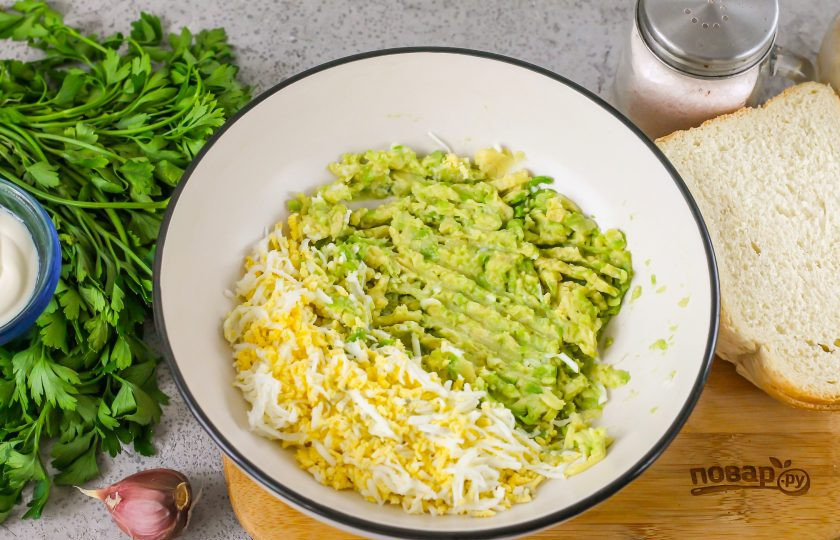 1. Этап. Бутерброды с авокадо и яйцом: Авокадо очистите от кожуры и удалите косточку. Выложите мякоть в глубокую емкость и помните вилкой. Отварные куриные яйца очистите от скорлупы и промойте в воде, натрите на терке с мелкими ячейками. Сбрызните массу из авокадо лимонным соком, чтобы она не потемнела.