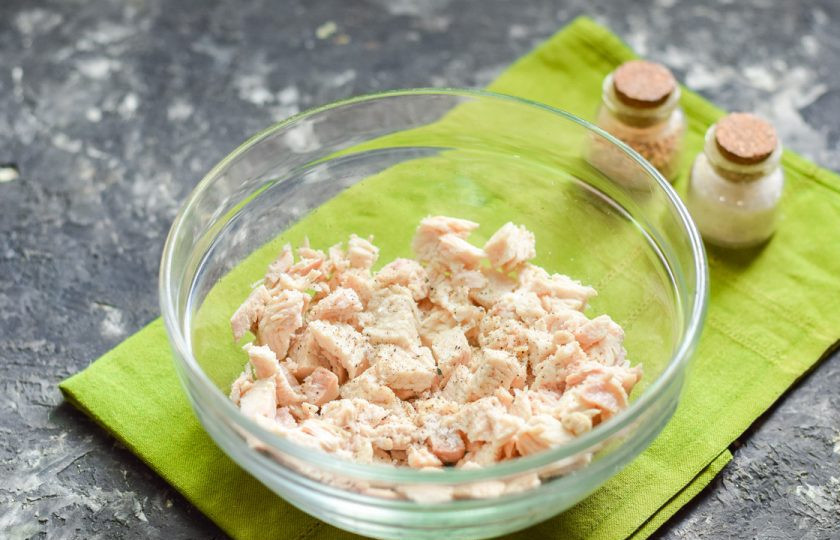 1. Этап. Салат Необыкновенная нежность: Куриное филе нарежьте небольшими кубиками и выложите первым слоем в салатник. Посолите и поперчите.