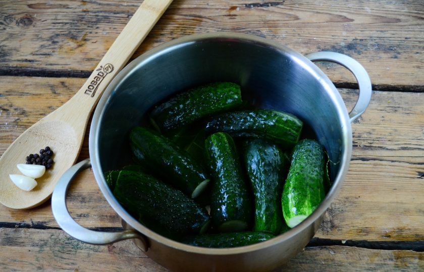 1. Этап. Малосольные огурцы за сутки: Подготовьте небольшую глубокую кастрюлю, в которой будете готовить малосольные огурцы. На дно кастрюли положите третью часть смеси зелени. Сверху выложите половину подготовленных огурчиков.