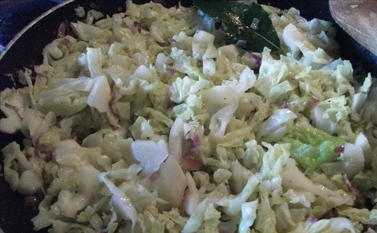 1. Этап. Капустник-пирог: В высокой сковороде обжарьте мелконарезанный репчатый лук и чеснок в оливковом масле. Добавьте нарезанную соломкой капусту, лавровый лист, приправьте солью, черным перцем и готовьте начинку в течение нескольких минут под крышкой, так, чтобы капуста осталась немного хрустящей. Снимите сковороду с огня и дайте начинке остыть.