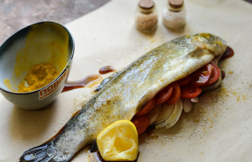 1. Этап. Форель в пергаменте в духовке: Внутрь рыбы выложите лук и помидоры. Полейте рыбу соком лимона и соевым соусом.