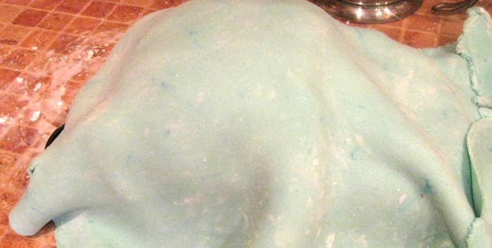 1. Этап. Торт на день рождения мальчику: И отправляем в холодильник минимум на час. По окончании этого времени раскатываем большой пласт голубой мастики, которую с помощью скалки переносим на машину. Если мастика блеклая - красим пищевым красителем, растворенным в водке, с помощью губки. Не бойтесь, водка испариться.