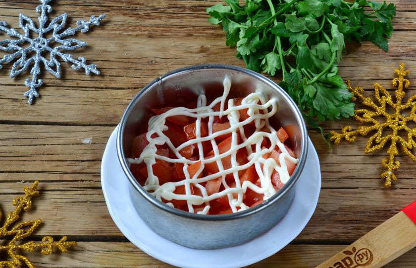 1. Этап. Салат Коррида с крабовыми палочками: На тарелку установите сервировочное кольцо. Первым слоем выложите помидорную массу, сверху покройте сеточкой майонеза.