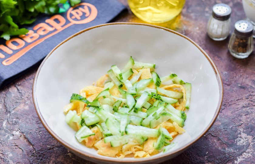 1. Этап. Салат из куриных сердечек: Свежий огурец сполосните и просушите, нарежьте небольшими полосками и добавьте в салатник.