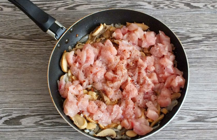 1. Этап. Энчиладос с курицей в лаваше: Добавьте к обжаренным луку и грибам куриное филе. Посолите, добавьте перец. Обжаривайте 5 минут.