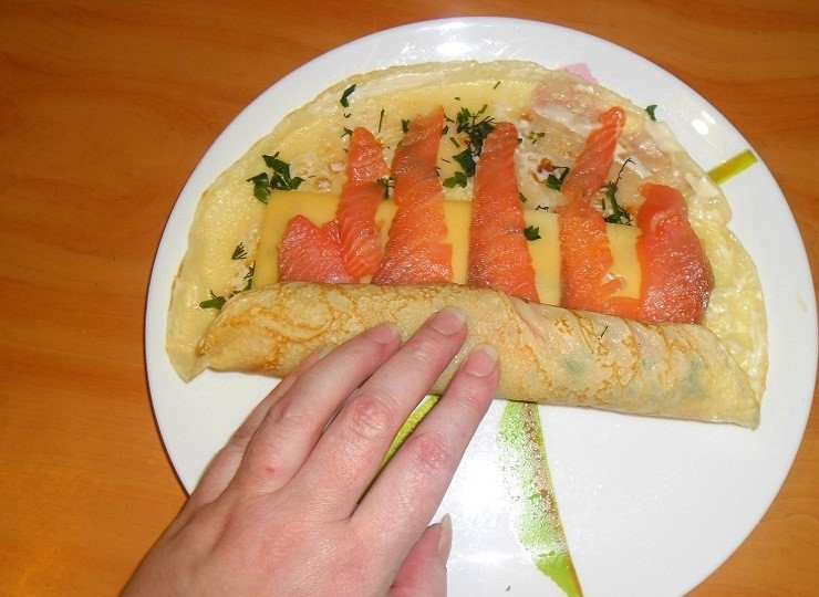 1. Этап. Блины с красной рыбой и огурцом: Сверните рулетик. Заверните в пищевую пленку. Аналогично приготовьте все рулеты. Затем отправляйте их в холодильник на пару часов, чтобы они не рассыпались при нарезке.